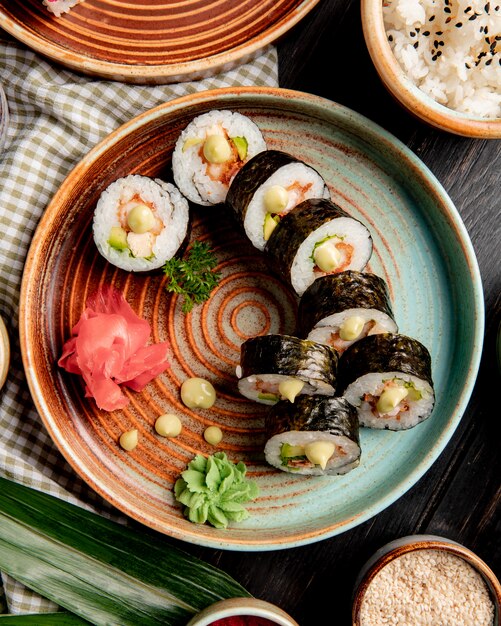 top vie of sushi rolls with tempura shrimps avocado and cream cheese on a plate with ginger and wasabi