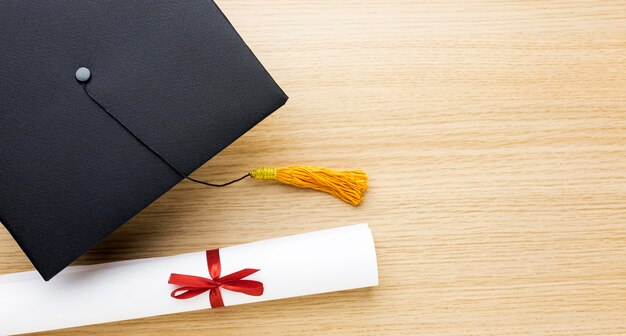 Top view of academic cap with diploma and copy space