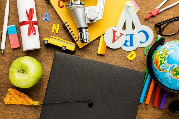 Top view of academic cap with school supplies and apple