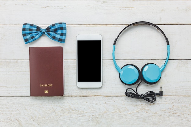 Top view accessoires to travel with man clothing concept. bow tie,passport on wooden background.headphone on wood table.