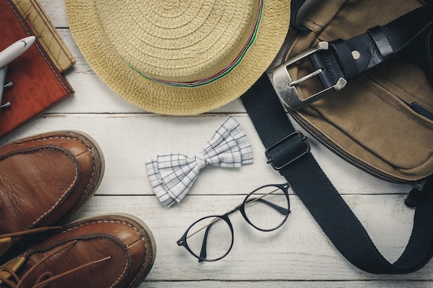 남자 의류 개념 여행 상위 뷰 액세서리. 나무 background.watch, 안경, 가방, 모자, 비행기, 흰색 나무 테이블에지도에 나비 넥타이.
