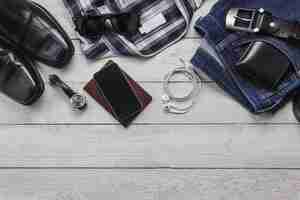 Free photo top view accessoires to travel with man clothing concept. shirt,jean,mobile phone on wooden background.watch,sunglasses and shoes on wood table.