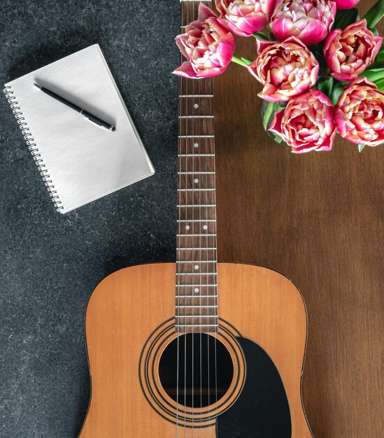 Top view acoustic guitar notepad and tulips on the table