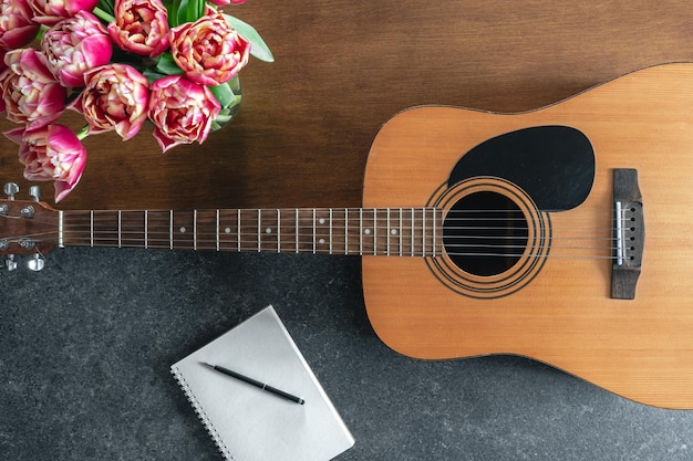 Free photo top view acoustic guitar notepad and tulips on the table