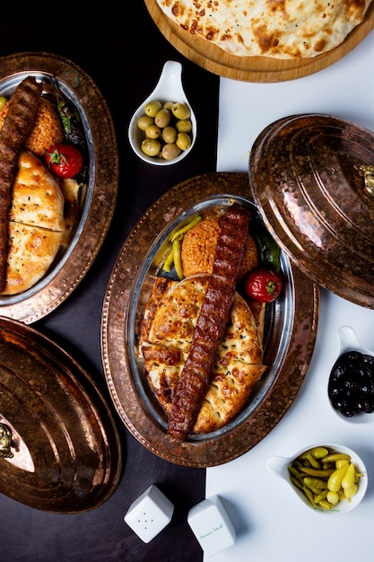 Top view of adana kebab served on tandoor bread and bulgur