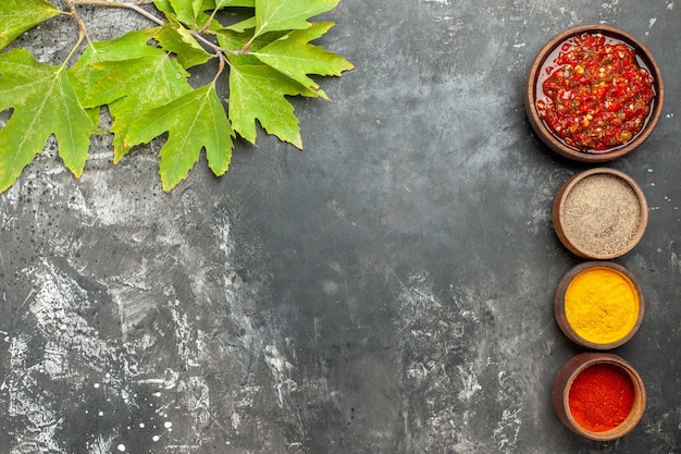 Free photo top view adjika in wooden bowl different spices adjika in small bowls on grey background