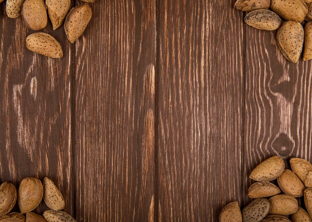 Top view of almonds in shell scattered on wooden background with copy space