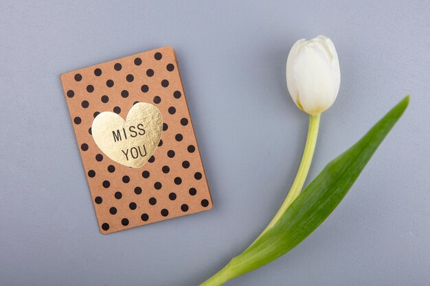 Top view of amazing white tulip with love card on a gray background