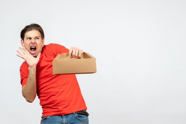 Top view of angry nervous and emotional young man in red blouse holding box on white background