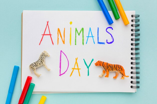 Top view of animal figurines and multicolored writing on notebook for animal day