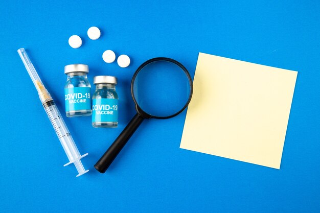 파란색 배경 병원 건강 covid- 과학 유행성 바이러스 약물에 돋보기 백신 및 알약으로 상위 뷰 바이러스 백신 주입