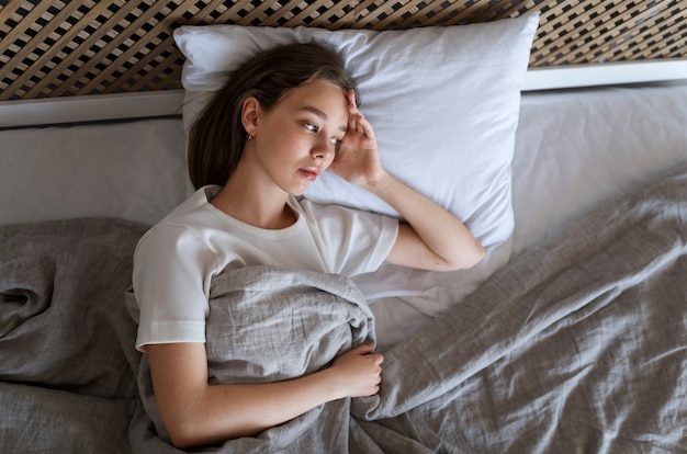 Foto gratuita donna ansiosa vista dall'alto sdraiata a letto