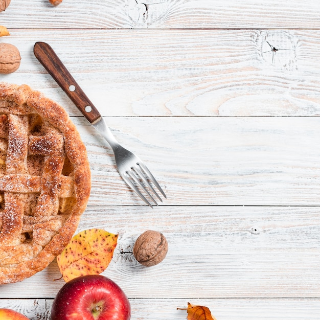 Free photo top view of appetizing pie with fork and apple