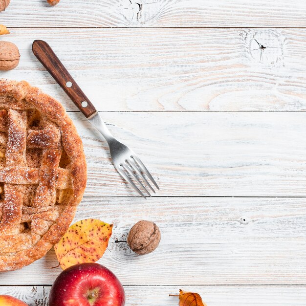 Top view of appetizing pie with fork and apple