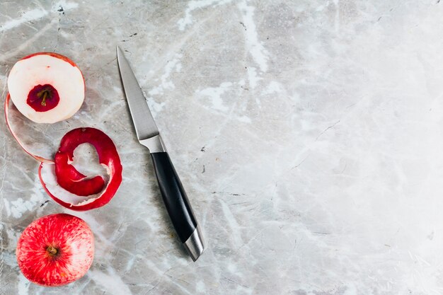Top view of apple and knife on marble background with copy space