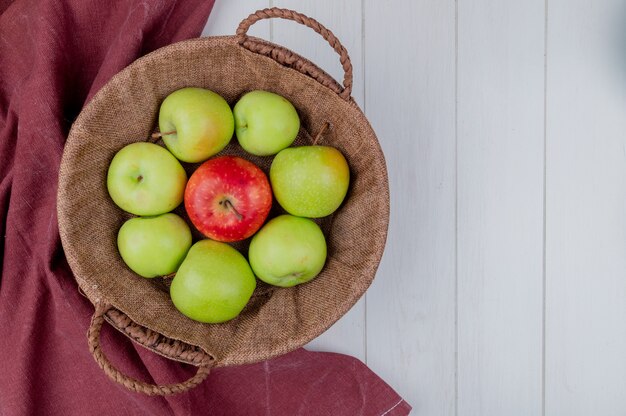Bordo布とコピースペースを持つ木製の背景上のバスケットにリンゴのトップビュー