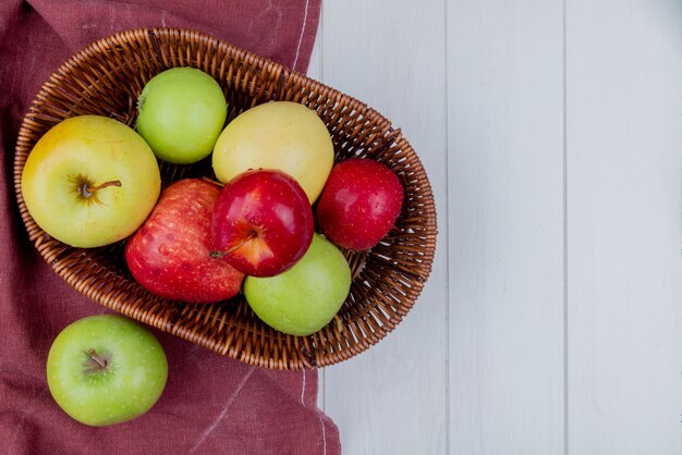 Top view of apples in basket on bordo cloth and wooden background with copy space