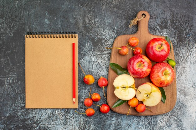 Top view apples the cutting board with apples cherries notebook pencil