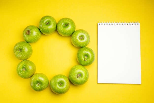 Top view of apples green apples next to the white notebook