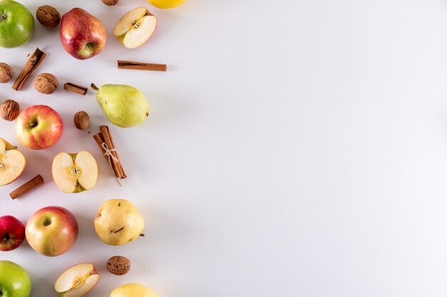 Top view apples half sliced with cinnamon and pear with copy space on right on white