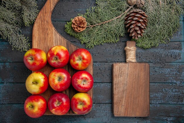 無料写真 灰色の表面に9つの黄赤リンゴと木の枝の間のまな板に乗った上面図のリンゴ