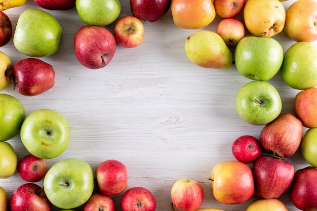 Foto gratuita frutta fresca delle mele e delle pere di vista superiore con lo spazio della copia nel mezzo su di legno bianco