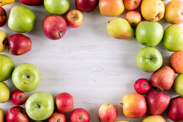 Top view apples and pears fresh fruits with copy space in middle on white wooden