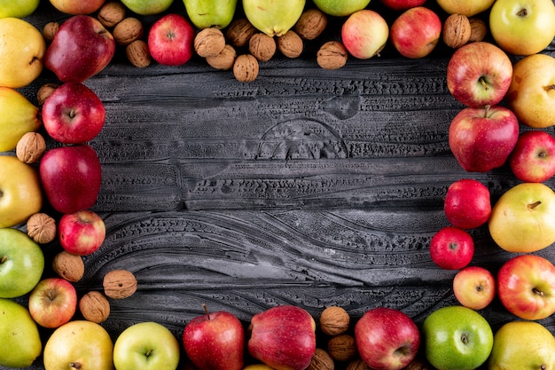 Top view apples and pears with nuts and walnuts with copy space on gray wooden  horizontal