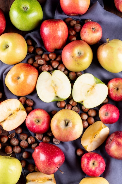 Top view apples with nuts on gray cloth on brown wooden  vertical