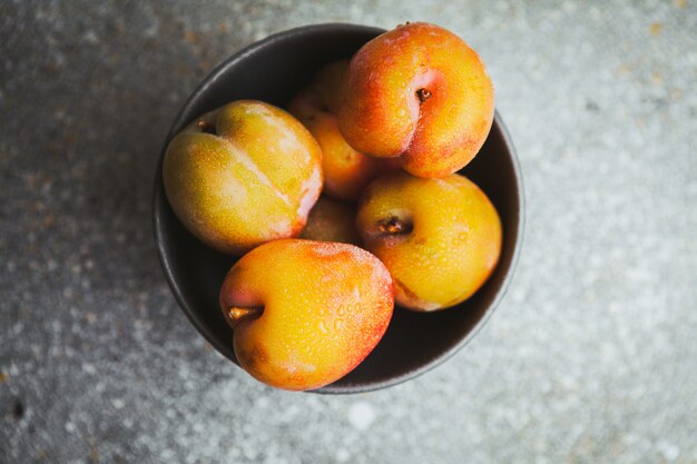 Top view apricots in bowl on gray textured.