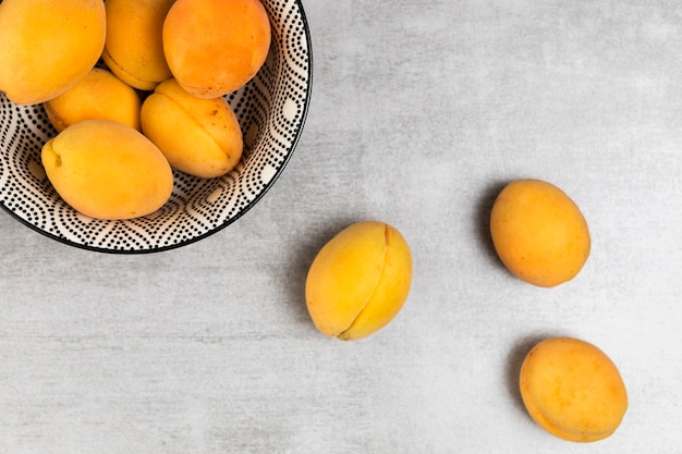 Free photo top view of apricots in bowl on wooden background