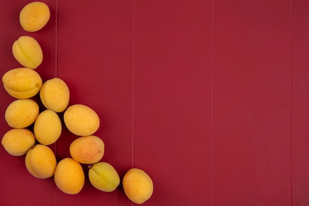 Free photo top view of apricots on a red surface