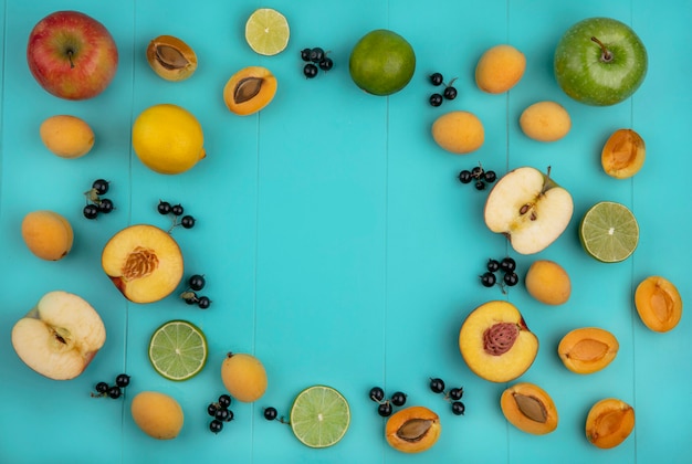 Top view of apricots with apples lemon with black currant with lime slices on a light blue surface