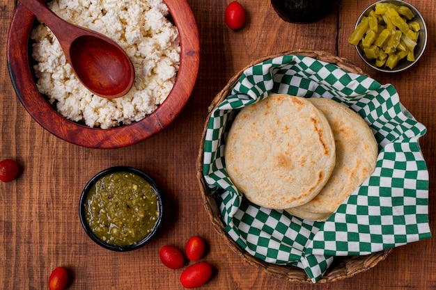 Free photo top view of arepas in basket with sauce and cherry tomatoes