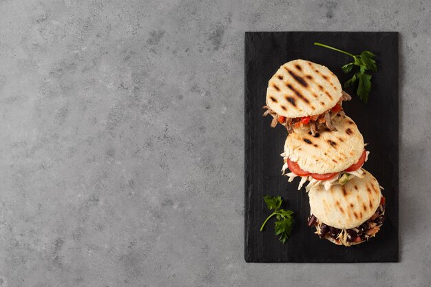 Top view arepas with meat and tomatoes