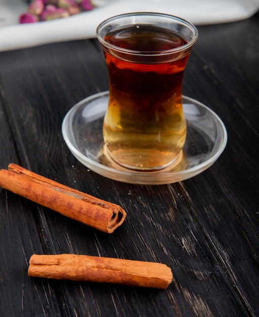 Free photo top view of armudu glass of tea with cinnamon sticks on wood