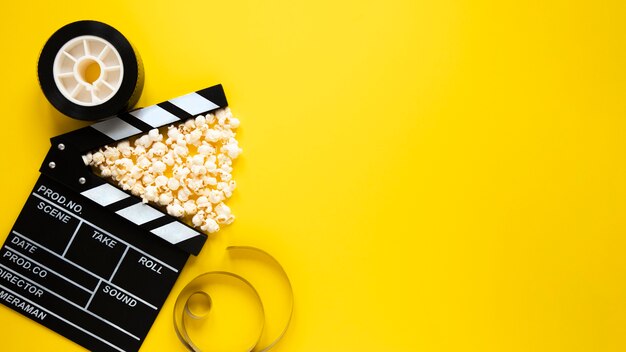 Top view arrangement of cinema elements on yellow background with copy space