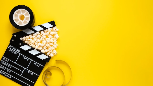 Top view arrangement of cinema elements on yellow background with copy space