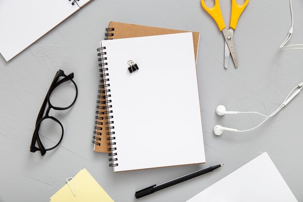 Top view arrangement of desk elements with empty notebook