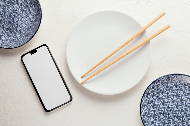Расположение элегантной посуды сверху со смартфоном