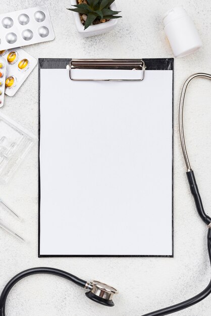 Top view arrangement on medical desk with empty clipboard