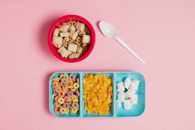 Top view arrangement with cereals in bowl and pink background