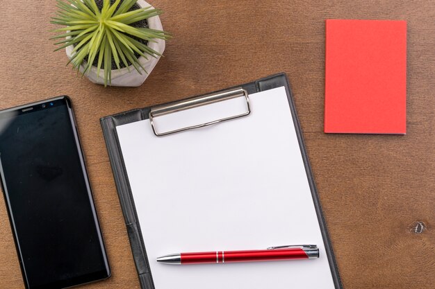 Top view arrangement with clipboard and smartphone