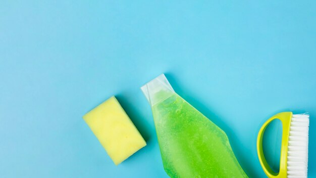 Top view arrangement with green detergent, sponge and brush