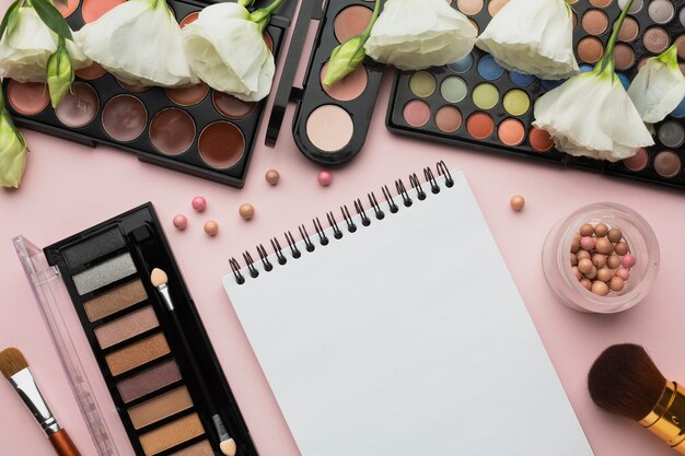 Top view arrangement with make-up items and notebook