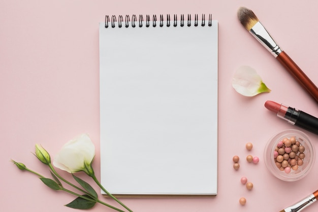 Top view arrangement with make-up products and notebook