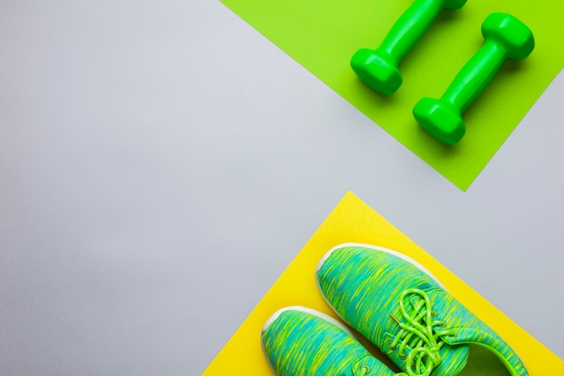 Top view arrangement with running shoes and dumbbells 