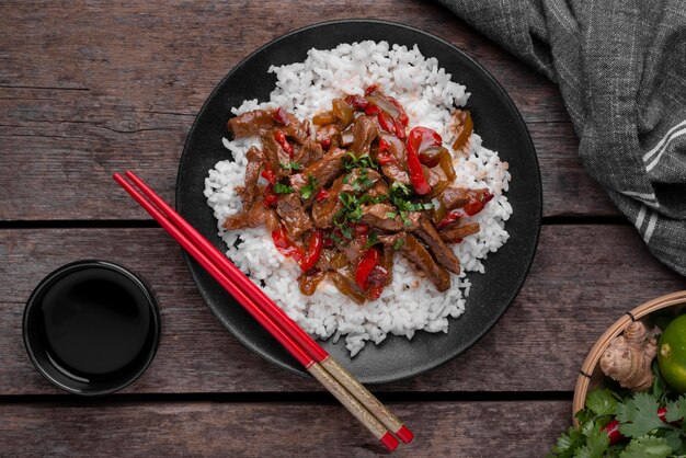 Top view of asian rice dish with meat and chopsticks