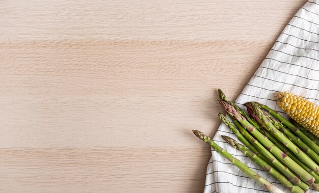 Top view asparagus and corn on kitchen towel with copy-space