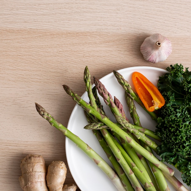 Top view asparagus, pepper and kale on plate with ginger and garlic